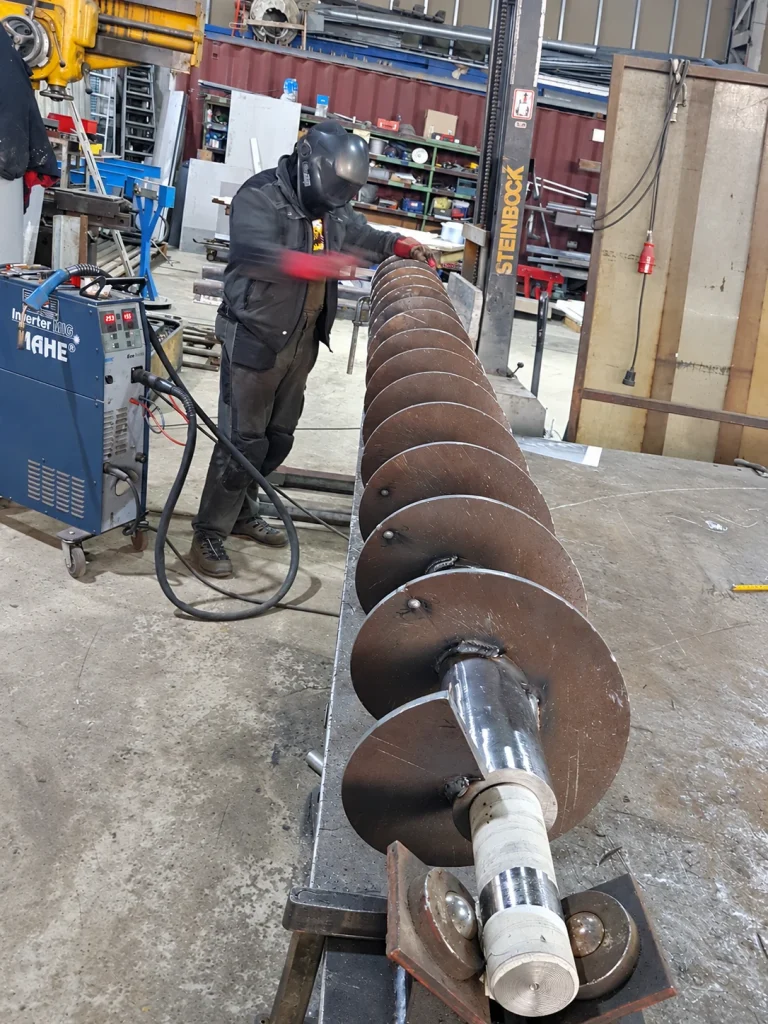 Mitarbeiter an einem metallischen Werkstück in der Werkstatt